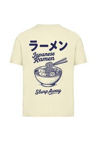 Krémové tričko s námořnickou modrou grafikou misky ramen s hůlkami. Text zní "ラーメン Japonské Ramen Slurp Away."