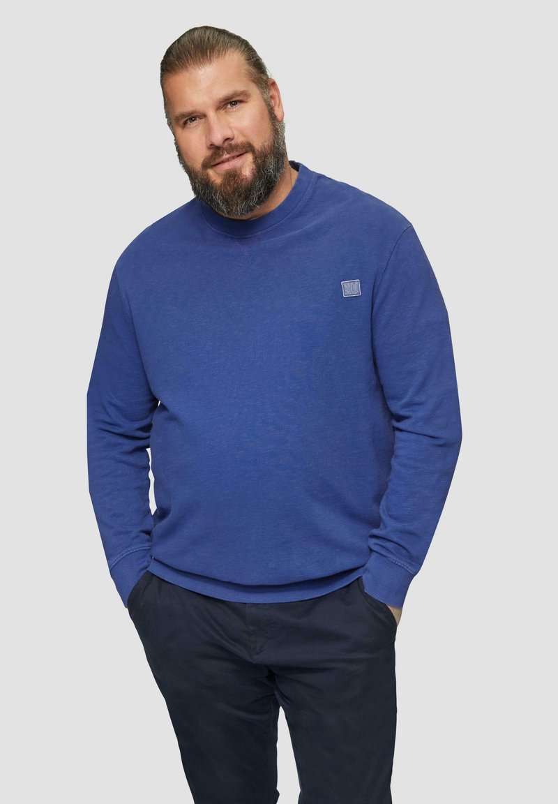Blauwe sweatshirt van katoenmateriaal, met lange mouwen, ribgebreide manchetten en een klein logo op de borst. Gemaakt met een marineblauwe broek.