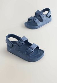 Sandale albastre din plastic cu două curele reglabile cu cataramă, talpă interioară texturată și talpă de cauciuc. Design cu vârf rotund și curea pentru suport la spate.