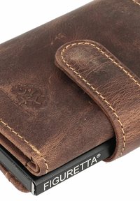 Bruine leren portemonnee met een gestructureerde afwerking, voorzien van een gestikte rand en een zichtbare sluitingsriem. Logo geperst op het oppervlak.