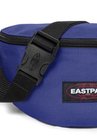 Modrá látková ledvinka s pevným černým popruhem a plastovou sponou. Obsahuje viditelnou nášivku s logem v červených a černých detailech.