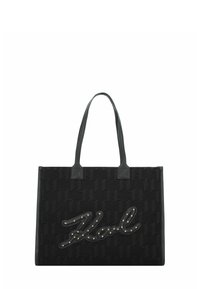 Zwarte tote bag van textuurstof, met een groot reliëf merklogo uitgerust met metalen studs. Verticale leren handvatten. Rechte vorm.