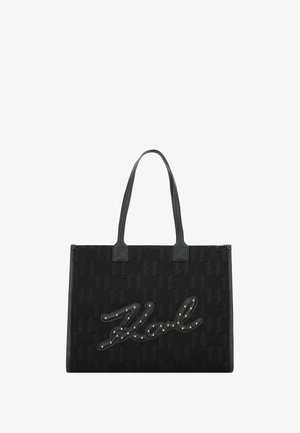 Sac fourre-tout noir en tissu texturé, doté d'un grand logo de marque en relief agrémenté de clous métalliques. Poignées en cuir verticales. Forme rectangulaire.