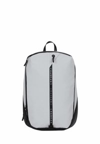 Sac à dos en tissu gris avec des accents noirs, doté d'une poignée supérieure, d'une fermeture éclair et d'une impression de logo vertical sur le devant.