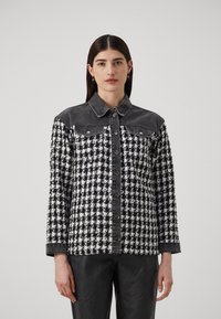 Bunda s čierno-bielym vzorom houndstooth s denimovými akcentmi, zapínanie na gombík a dlhé rukávy. Textúrovaná tkanina, dizajn s golierom.