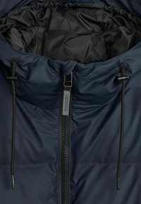 Navy blue puffer jacketin sisällä mustalla vuorilla, etuosassa vetoketju ja kauluksessa kiristimet säädettäväksi sulkemiseksi.