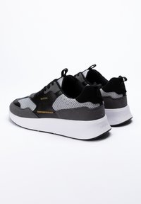 Baskets noires et grises en mesh et daim. Comporte des accents dorés, une semelle blanche épaisse et un design supérieur texturé.