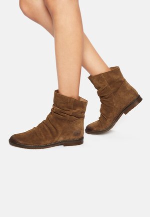Bottines en daim marron avec un design décontracté, bout arrondi, talon bas et détails cousus. Comprend un logo sur le côté extérieur.