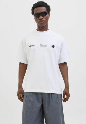 Hvid bomulds T-shirt med korte ærmer, prydet med sort "Riptide" tekst og en solgrafik på brystet, parret med grå bukser.