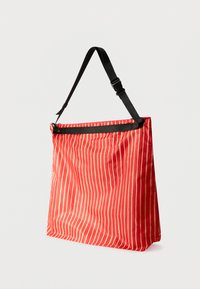 Τσάντα ώμου με κόκκινες ρίγες και μαύρο λουράκι. Κατασκευασμένη από ελαφρύ, υφή υλικό. Διαθέτει κλείσιμο με φερμουάρ στην κορυφή και απλό σχεδιασμό.