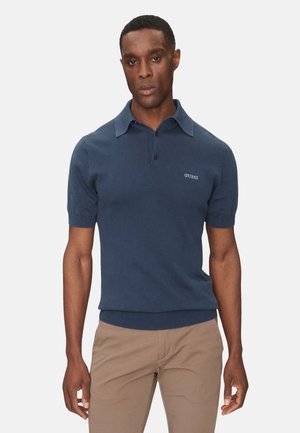 Polo de manga corta azul marino hecho de algodón, con cuello doblado, tapeta de botones y un pequeño logo bordado en el pecho.