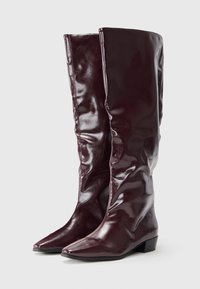 Knee-high burgundy boots made of glossy synthetic material, featuring a streamlined design, pointed toe, and low block heel.