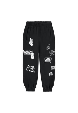 Pantalons de jogging noirs avec taille et poignets élastiques, présentant divers imprimés graphiques blancs et patchs, y compris des symboles de paix et des thèmes spatiaux.