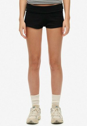 Zwarte sportshorts met een brede tailleband, gecombineerd met beige sneakers en witte crew-sokken. Glad materiaal, aansluitend ontwerp, minimalistische stijl.