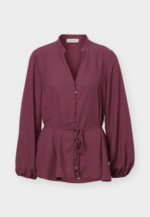 Blouse prune à manches longues avec col mandarin, boutons dorés sur le devant et ceinture à la taille, avec un ourlet légèrement évasé et des poignets froncés.