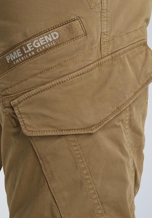 Beige cargo pants with a textured fabric featuring a prominent flap pocket and stitched details. Logo patch on the waistband.