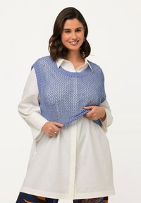 Ljusblå stickad top lagd över en vit skjorta med knappar, med en lös, öppen väv och vid halsringning.