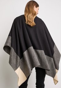Sort og grå poncho med et trekantet design; leveres i blødt uldmateriale og beige accenter på kanterne. Tekstureret, falder løst.