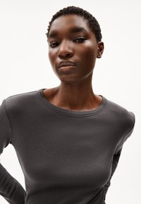 Dunkelgraues Langarmshirt mit rundem Ausschnitt und weichem, strukturiertem Stoff. Figurbetontes Design mit dezenten Nähten an den Schultern.