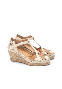 Sandales compensées avec un dessus en cuir crème, des accents dorés et une semelle en jute tressé. Conception à bout ouvert avec une bride T et des détails de couture.
