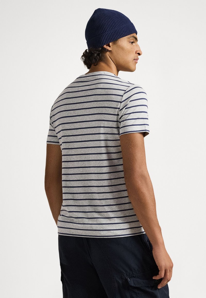 Grijs gestreept t-shirt met marineblauwe horizontale strepen, ronde hals, korte mouwen, gedragen met marineblauwe cargoshorts en een bijpassende muts.