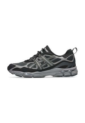 Baskets de sport noires et grises avec tige en mesh et synthétique, semelle épaisse rembourrée, fermeture à lacets et languette à l’arrière sur fond blanc.