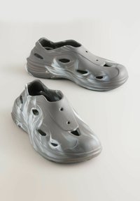 Grå, letvægts klipklappere med en glat, blank overflade, der har flere ventilationshuller og et marmor mønster på siderne.