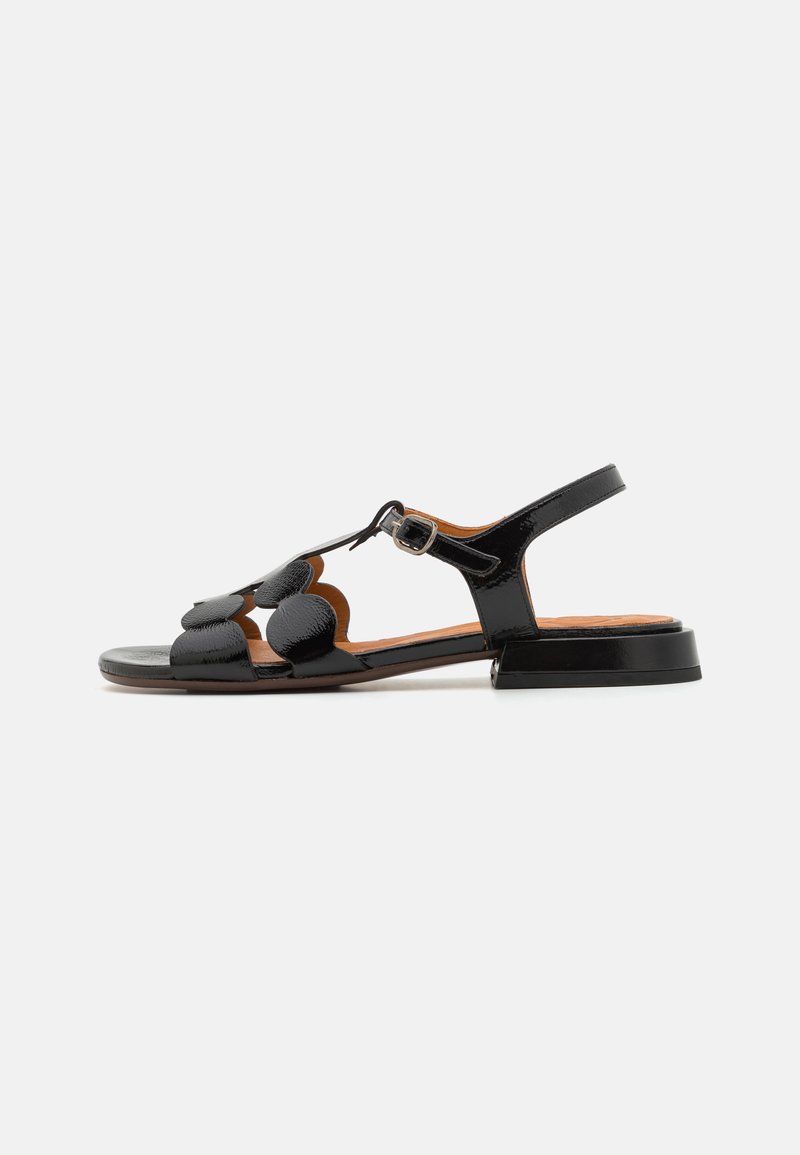 Sandalo in pelle patent nera con design a T, decorazioni circolari, cinturino alla caviglia regolabile e tacco basso a blocco.