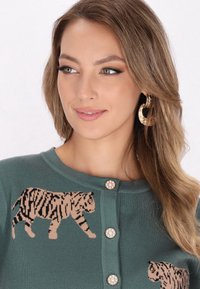 Cárdigan de punto verde con dos motivos de tigre en marrón y negro. Acentuado con botones en forma de perlas en la parte delantera y un clásico cuello redondo.