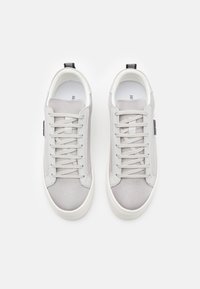 Baskets grises avec une tige en mesh et en cuir, design à lacets, bout rond et une semelle en caoutchouc blanc avec un accent noir au talon.