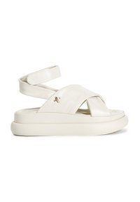 Bílé kožené sandály s křížovým designem, plochou podrážkou a řemínkem kolem kotníku. Mají jemný kovový akcent po straně.