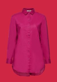 Chemise magenta à manches longues, boutonnée, avec col et ourlet courbé sur fond rouge uni.