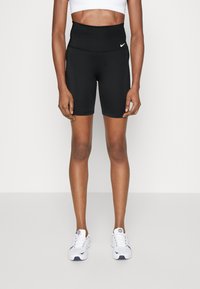 Shorts de sport noirs taille haute en tissu extensible à texture lisse, avec un petit logo Nike blanc à l'avant.