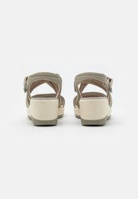 Beige platform sandals with a textile upper, adjustable ankle strap, and cushioned footbed; features a chunky, lightweight heel.
