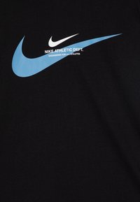 T-shirt noir avec un grand logo en forme de swoosh bleu clair et un texte blanc indiquant "NIKE ATHLETIC DEPT. CONÇU POUR TOUS LES ATHLÈTES."