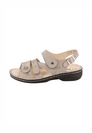 Sandalo ortopedico beige con cinturini regolabili, suola imbottita, punta aperta e cinturino posteriore con fibbia su suola ergonomica nera.