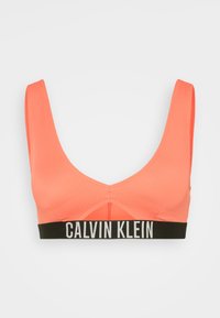 Koralle Sport-BH mit gerippter Textur, breiten Trägern und einem schwarzen, markierten elastischen Band mit "CALVIN KLEIN" in weißer Schrift.