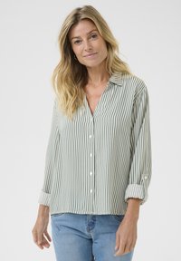Camicia a righe verde chiaro e bianca, con chiusura frontale a bottoni, colletto e maniche arrotolate; realizzata in un tessuto leggero.