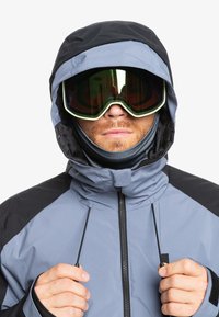 Skijacke in Hellgrau und Schwarz, mit verstellbarem Kapuzen, Reißverschluss vorne und Handwärmertaschen. Texturiertem Stoff mit elastischen Bündchen.