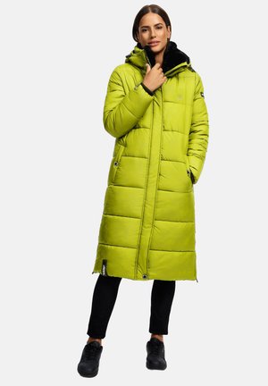 Woman wearing a long lime green padded coat with a hood, black pants, and black sneakers, standing against a plain background.