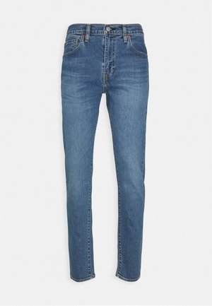 Jean en denim bleu à coupe droite, taille haute, design à cinq poches et décoloration subtile. Doté d'un bouton en métal et d'une fermeture éclair.