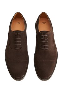 Une paire de chaussures de ville pour hommes en daim marron foncé, avec des lacets, présentant un bout chapeau et une doublure intérieure beige.