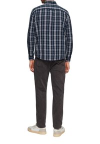 Marine geruite shirt met witte en lichtblauwe accenten, met knoopsluiting, lange mouwen. Gecombineerd met donkergrijze broek en witte sneakers.