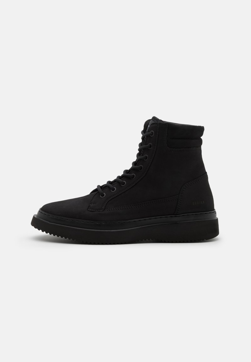 Botte noire montante à lacets avec col rembourré et semelle épaisse, vue de profil sur un fond clair uni.