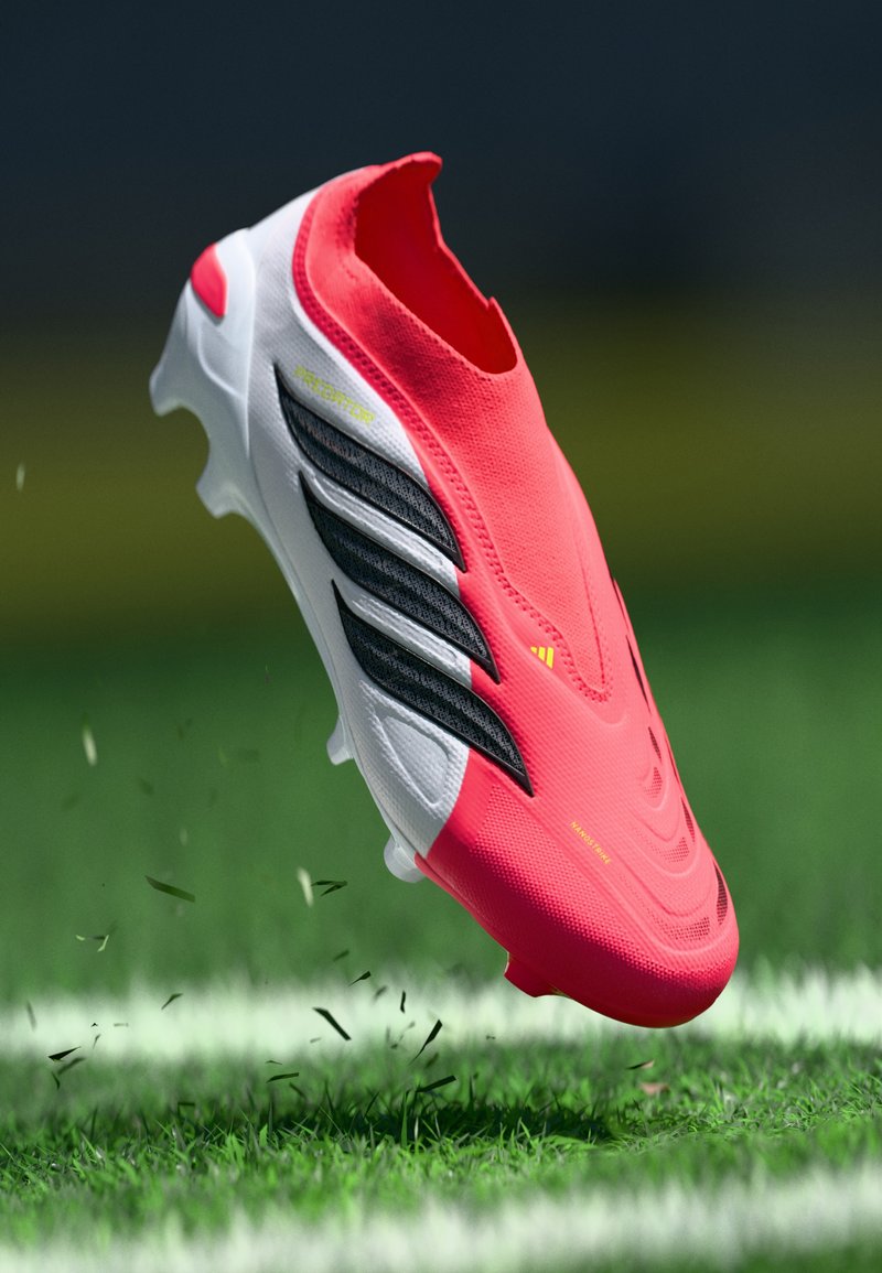 Rote und weiße Fußballschuhe mit schwarzen Akzenten, die ein schlankes Design, eine strukturierte Oberfläche und sichtbare Stollen für Traktion auf Rasen bieten.