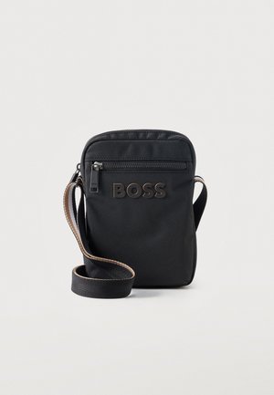 Sac bandoulière noir avec poche zippée à l'avant et logo "BOSS", bandoulière réglable avec bordure marron, sur fond clair.