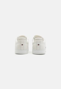Sneaker bianchi in pelle con una texture liscia, caratterizzati da un design low-top, forma arrotondata e un piccolo logo sulla parte posteriore.