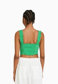 Zielony, krótki top z falbankami na ramiączkach i marszczonym wzorem. Posiada falbaniasty dół i otwarty tył.