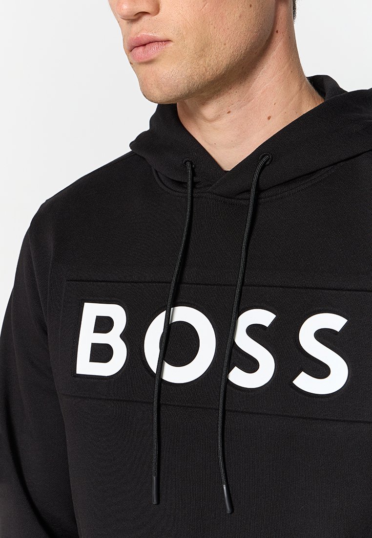 Sweat à capuche noir en tissu texturé avec un grand logo blanc "BOSS" sur le devant et des cordons de serrage réglables à la capuche.