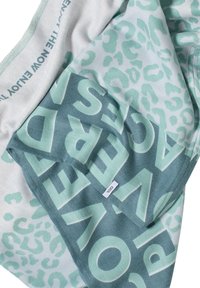 Tissu léger présentant un schéma de couleurs vert menthe et blanc avec un texte en gras et un motif léopard. Étiquette visible en bas à droite.